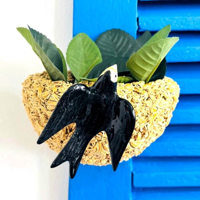 ninho de andorinha feito em cerâmica colocado numa parede azul