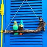 2 passarinhos de tecido azul claro, pousados num galho de madeira