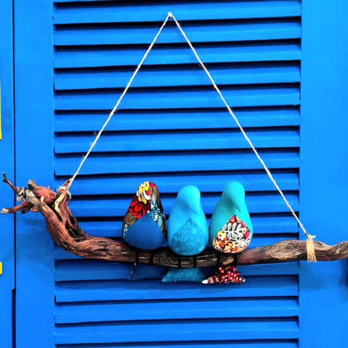 3 passarinhos de tecido azul pousados num galho de madeira