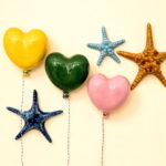 conjunto de balões com a forma de coração e estrelas do mar em ceramica de diversas cores