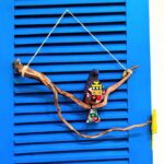 passarinhos de tecido roxo e com padrões, pousado num galho de madeira