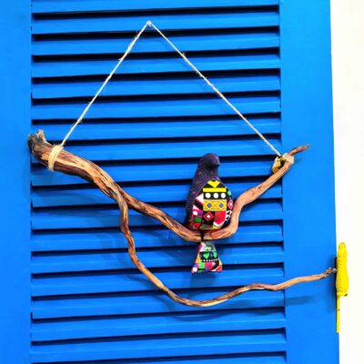 passarinhos de tecido roxo e com padrões, pousado num galho de madeira