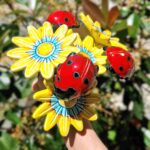 arranjo de flores amarelas com joaninhas vermelhas em ceramica