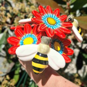 arranjo de flores vermelhas com abelhas em ceramica