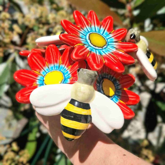 arranjo de flores vermelhas com abelhas em ceramica