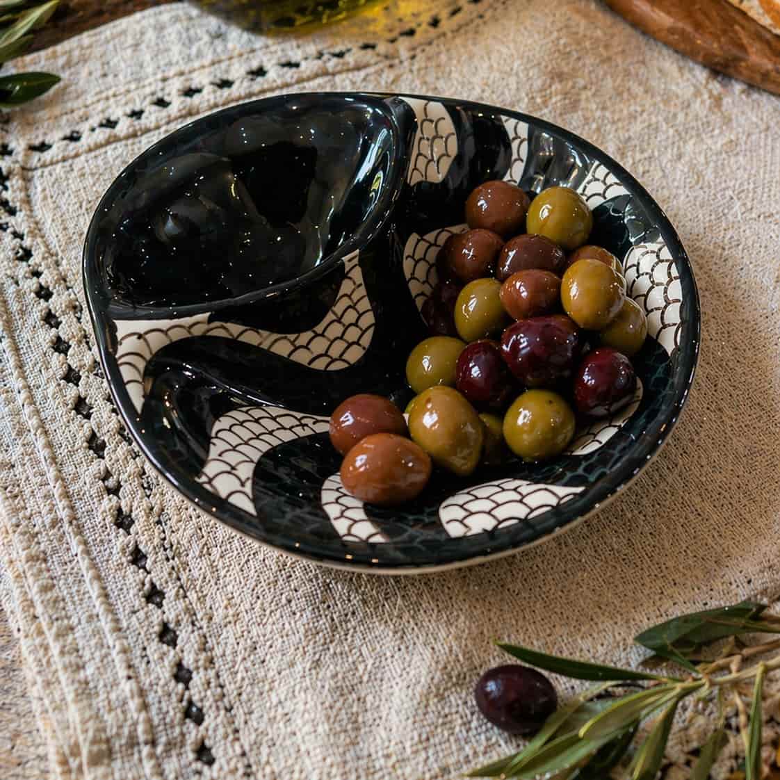 azeitoneira em cerâmica com padrão de calçada portuguesa com azeitonas, sobre uma mesa rustica