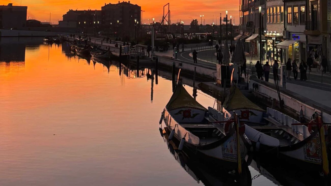 fotografia das ria de Aveiro ao por do sol com os moliceiros e os edifícios de arte nova