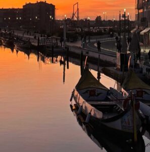 fotografia das ria de Aveiro ao por do sol com os moliceiros e os edifícios de arte nova