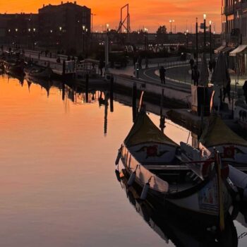 fotografia das ria de Aveiro ao por do sol com os moliceiros e os edifícios de arte nova
