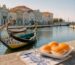 foto da ria de aveiro, com o barco moliceiros e o doce de ovos moles de aveiro