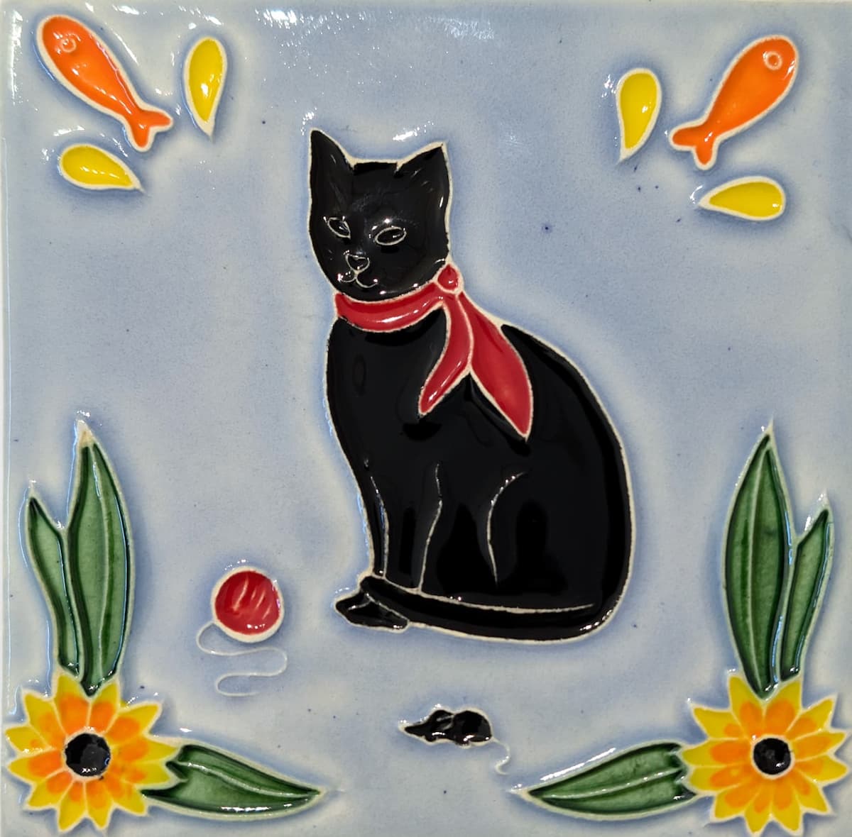 azulejo em relevo de gato preto de lenço vermelho ao pescoço, num fundo azul um ratinho preto, uma bola vermelha e flores azulejo em relevo de gato preto de lenço vermelho ao pescoço, num fundo azul um ratinho preto, uma bola vermelha e flores