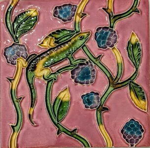 azulejo português em relevo de lagarto com plantas, num fundo cor de rosa