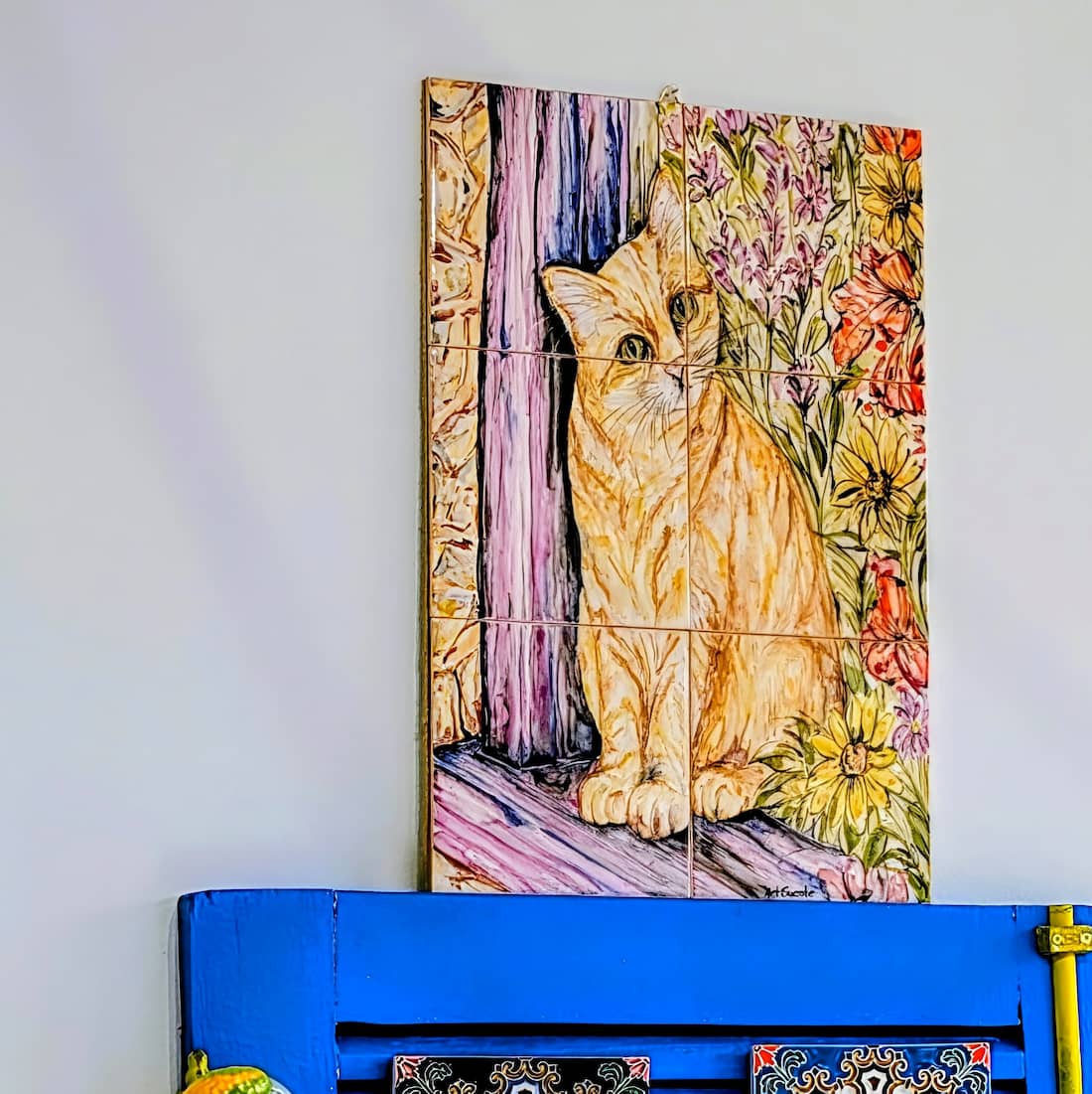 painel de azulejos com um gato sentado, pintado à mão na parede da loja portugal care aveiro