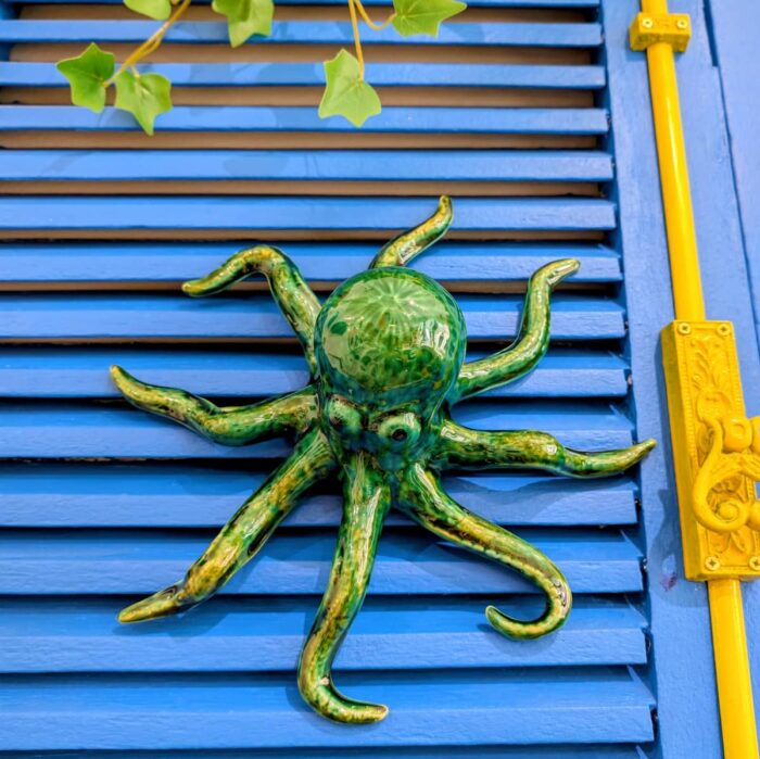 polvo em ceramica artesanal verde pendurado numa parede azul