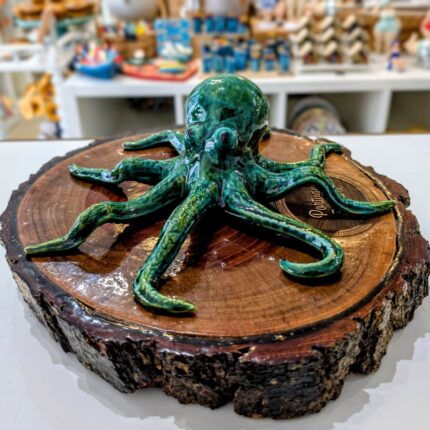 polvo em ceramica artesanal verde sobre um tronco de madeira castanha