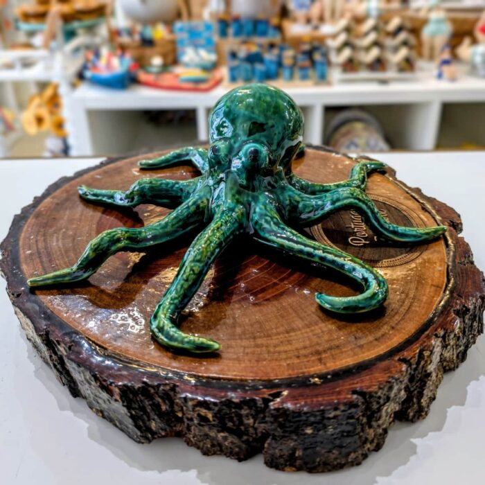 polvo em ceramica artesanal verde sobre um tronco de madeira castanha